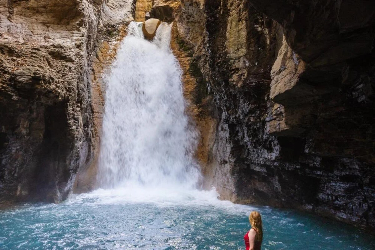 Traveler swimming beneath a tropical waterfall in Costa Rica